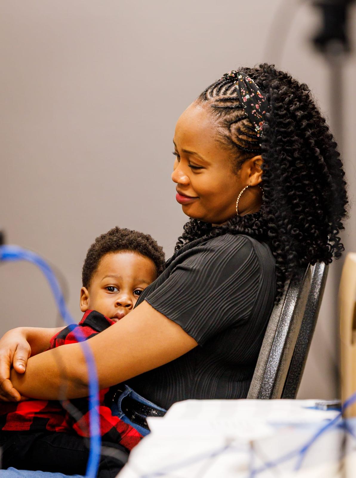 A mother holding her toddler close at a family event